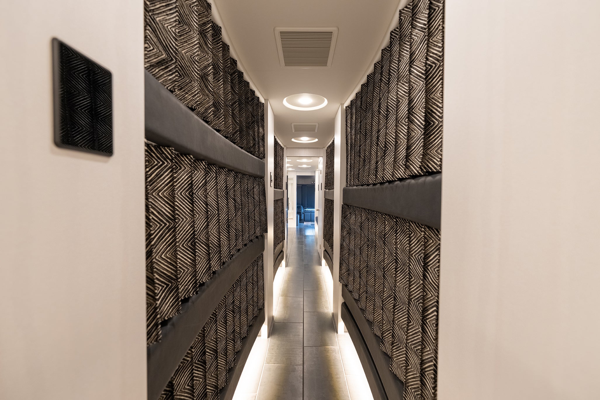 Long corridor with sleeping quarters on each side with curtains.