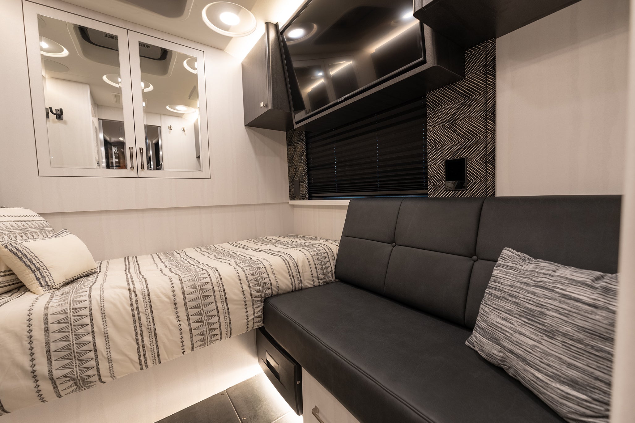 Interior of a vehicle with a bed and black leather bench.