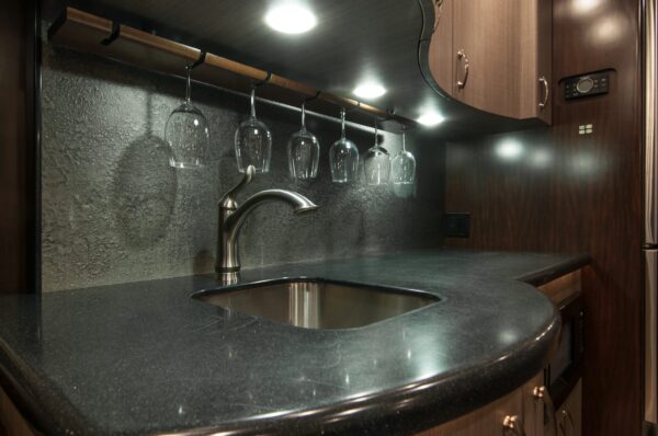 Modern kitchen with granite countertop, sink, and hanging glasses.