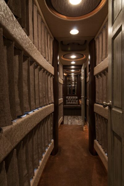 Long narrow hallway with brown carpet and wooden doors.