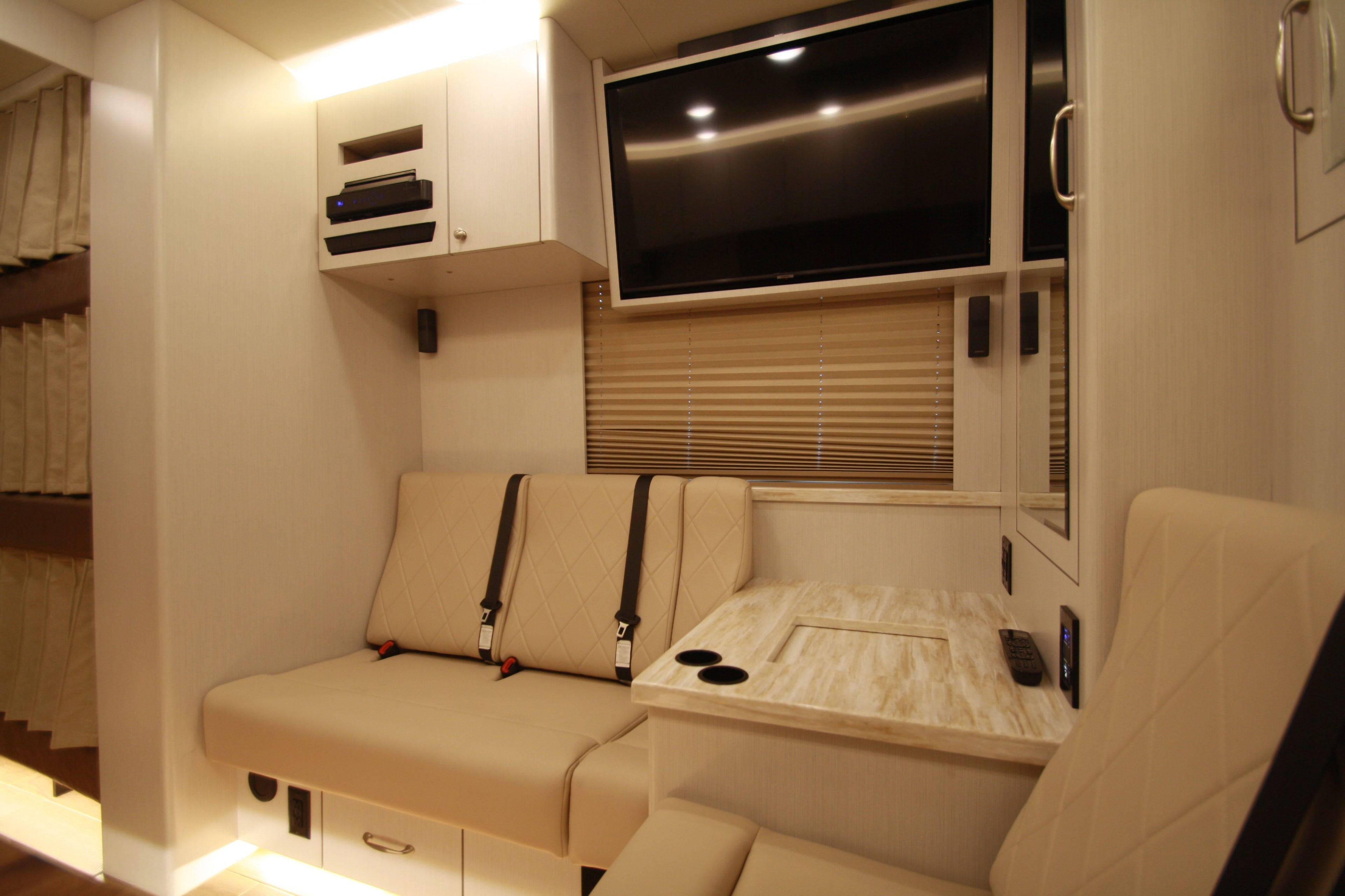 Interior of a compact living space with a couch, table, and TV.