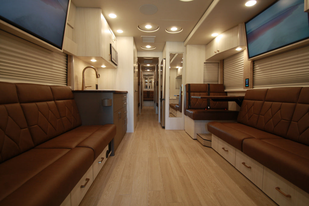 Modern interior of a bus with brown leather seats and wooden floor.