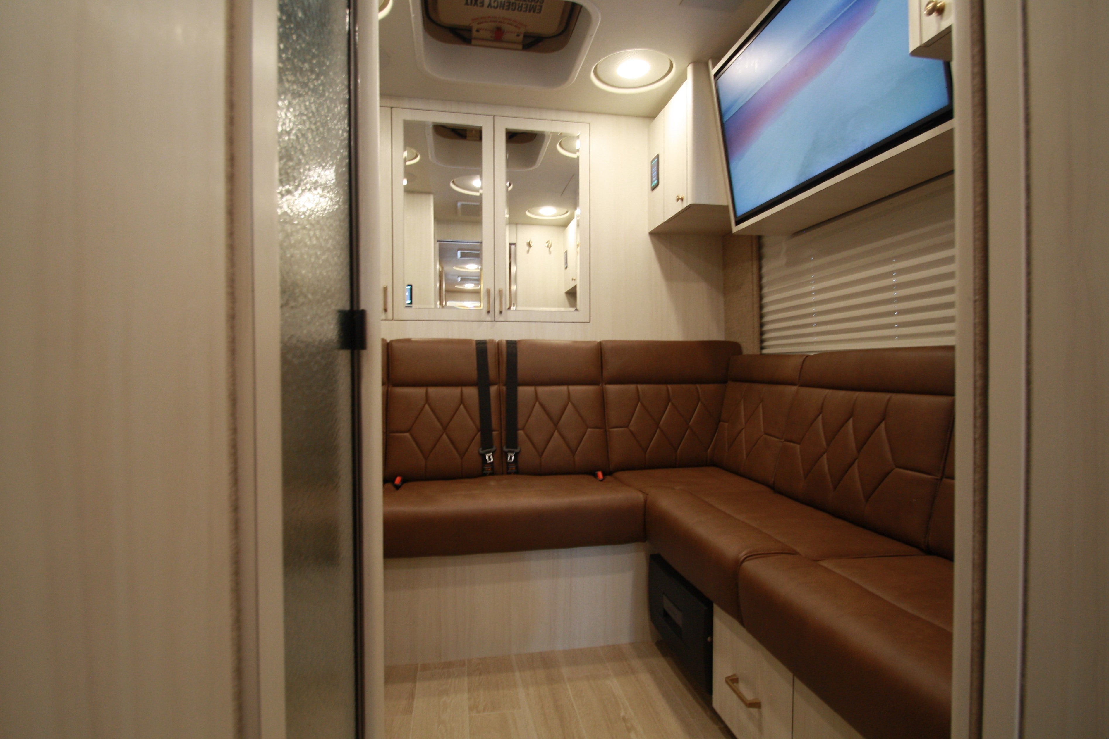 Interior of a vehicle with brown upholstered bench and a mounted screen.